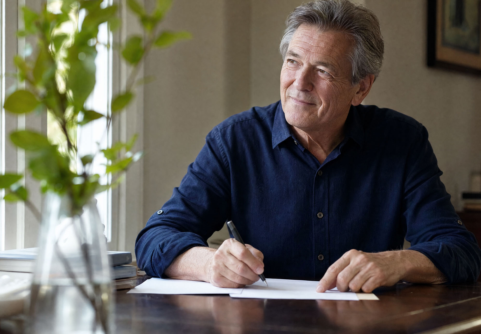 Man writing at a desk beside a window